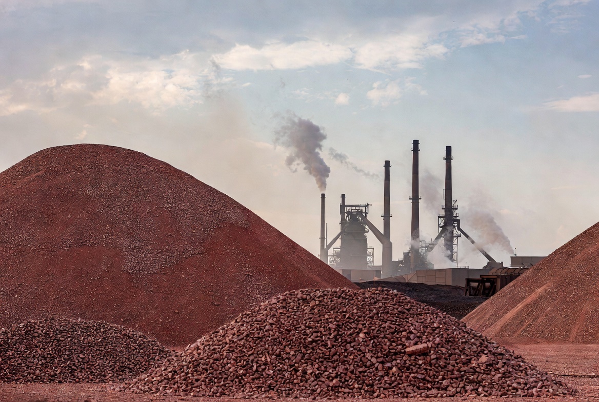 Copper ore processing facility with industrial smokestacks and large ore stockpiles