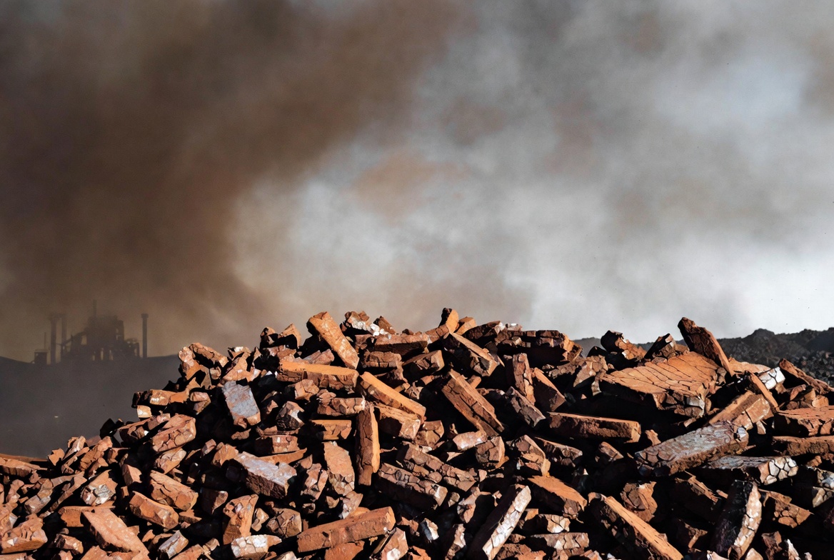 Pile of raw copper ore and industrial waste material under a cloudy sky